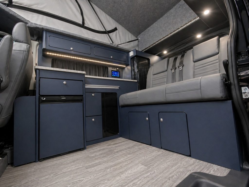 Insulated interior of an Escape Crusader Renault Trafic campervan with the pop top raised and lights on