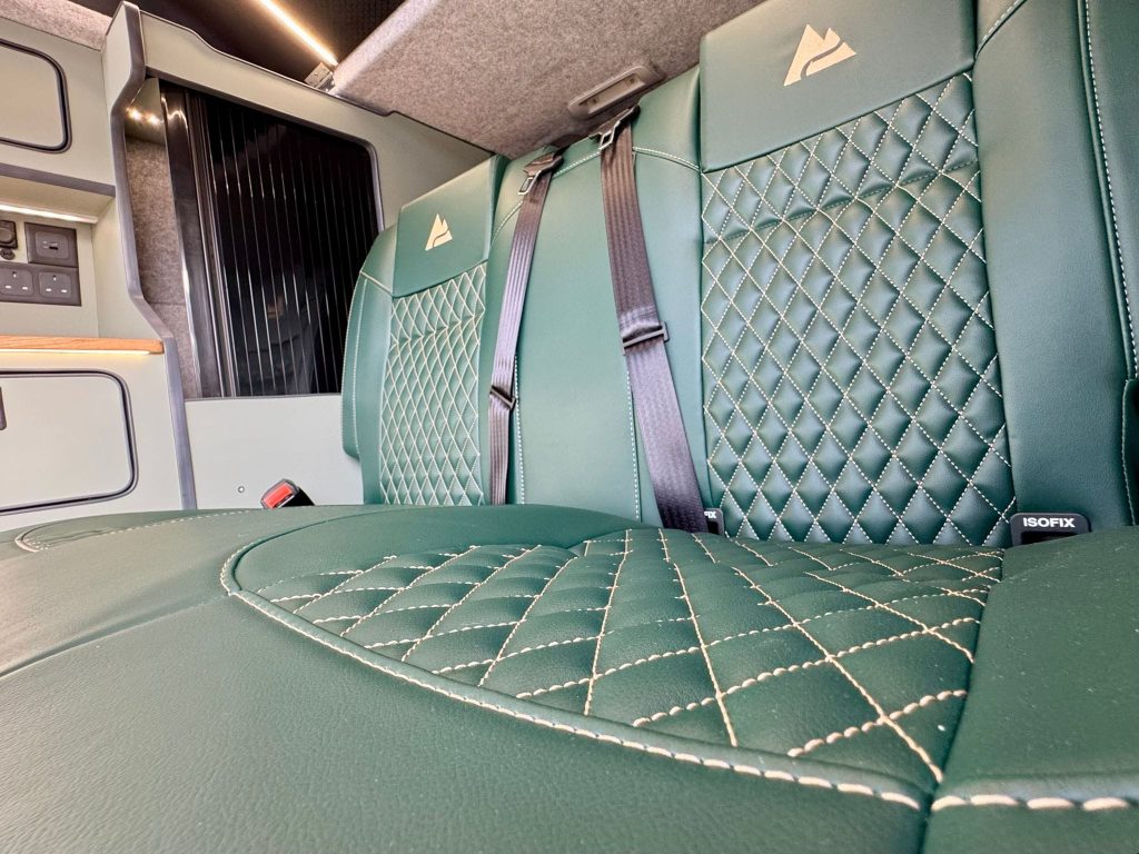 Close up of the seat belt and diamond stitched upholstery on a RIB seat bed in an Escape campervan