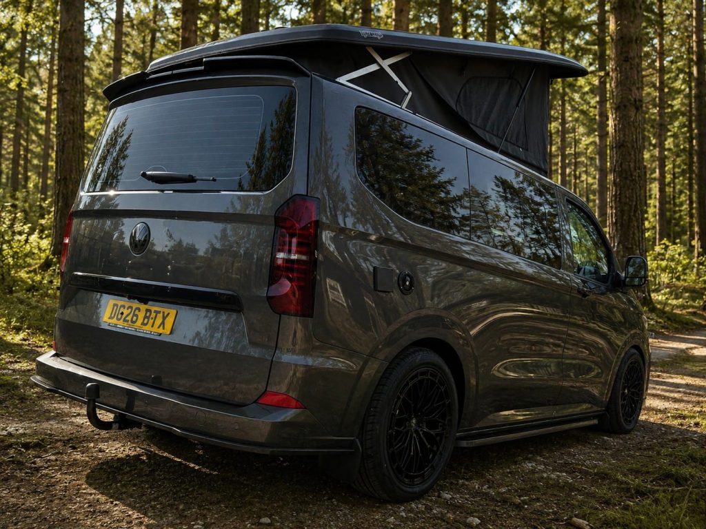 Rear view of a grey VW T7 Escape Breeze Plus campervan with the pop top raised on a woodland track