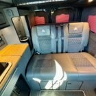 Inside an Escape Crusader campervan with a grey quilted leather seat bed, worktop and control panel
